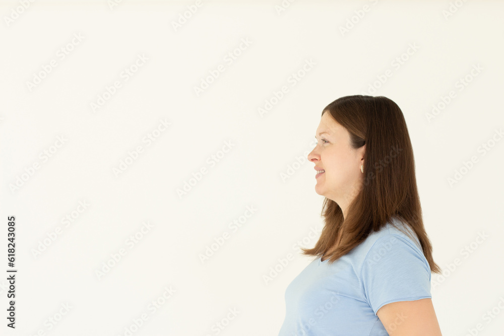Profile portrait of healthy natural woman, smiling and looking left at empty space, standing in blue t-shirt on white background. Profile portrait of healthy natural woman, smiling and looking left at empty space, standing in blue t-shirt on white background.