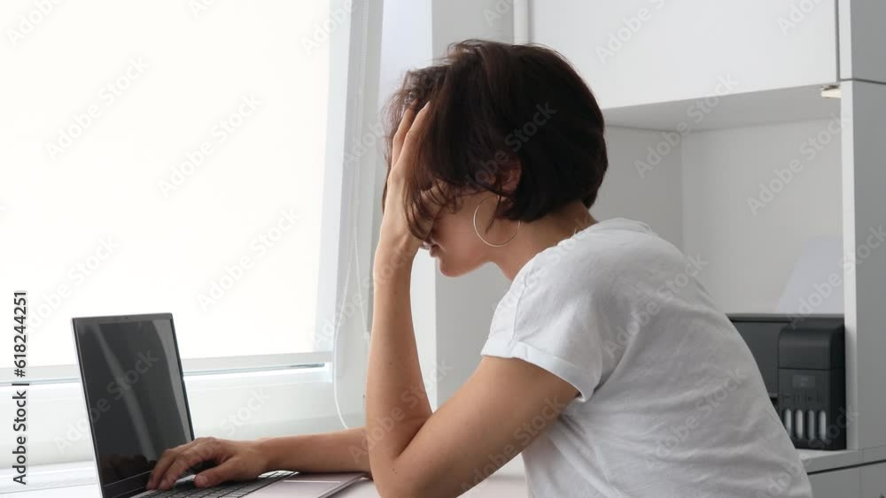 Tired, frustrated, exhausted, stressed woman sitting at desk working on laptop. Headache. Daylight work. Girl in White shirt Tired, frustrated, exhausted, stressed woman sitting at desk working on laptop. Headache. Daylight work. Girl in White shirt