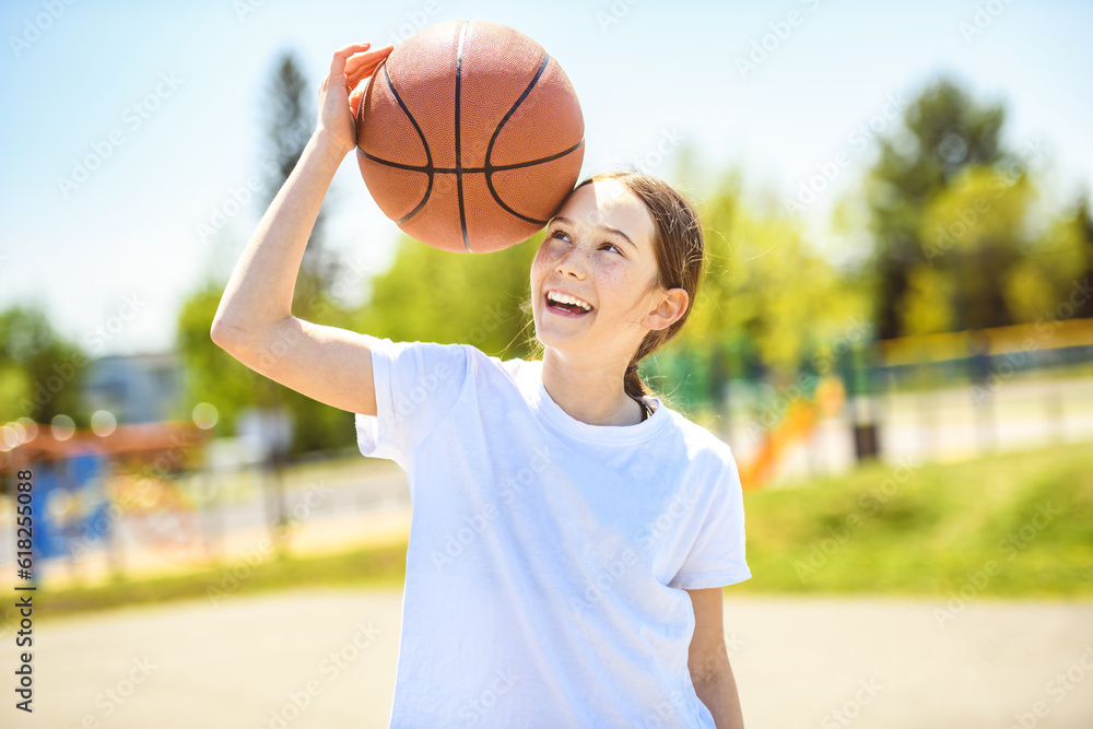 portrait of a kid girl playing with a basketball in park