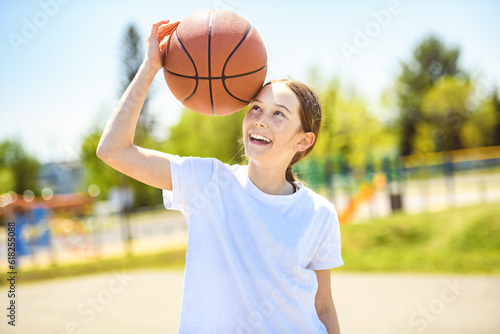 portrait of a kid girl playing with a basketball in park
