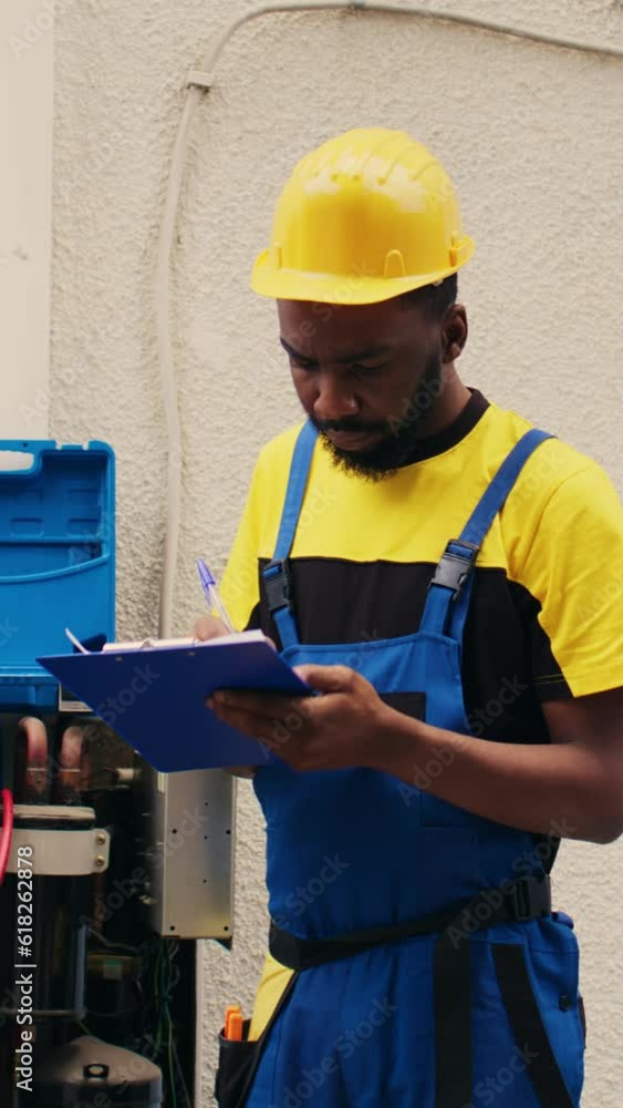 Vertical video Expert technicians team working with manifold gauges to check air conditioner refrigerant levels, writing result on clipboard. Skillful mechanics using barometer benchmarking hvac Vertical video Expert technicians team working with manifold gauges to check air conditioner refrigerant levels, writing result on clipboard. Skillful mechanics using barometer benchmarking hvac