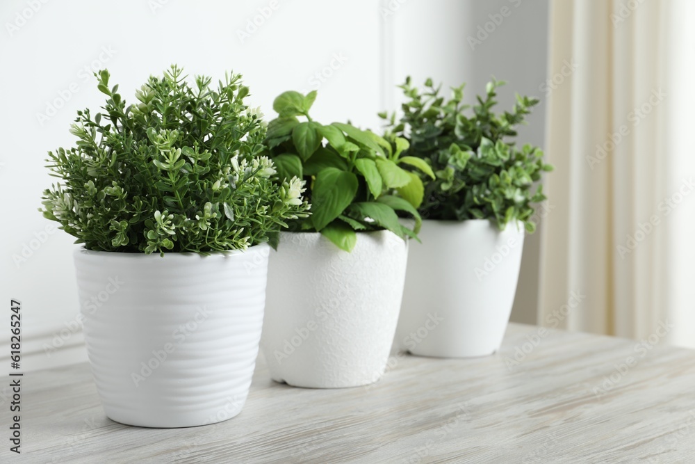 Different artificial potted herbs on white wooden table indoors, space for text Different artificial potted herbs on white wooden table indoors, space for text