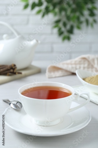 Aromatic licorice tea in cup and spoon on white table, space for text