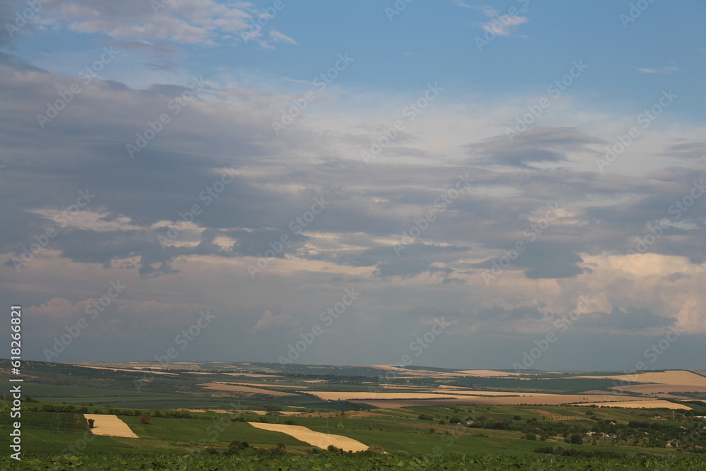 A landscape with a field and clouds in the sky