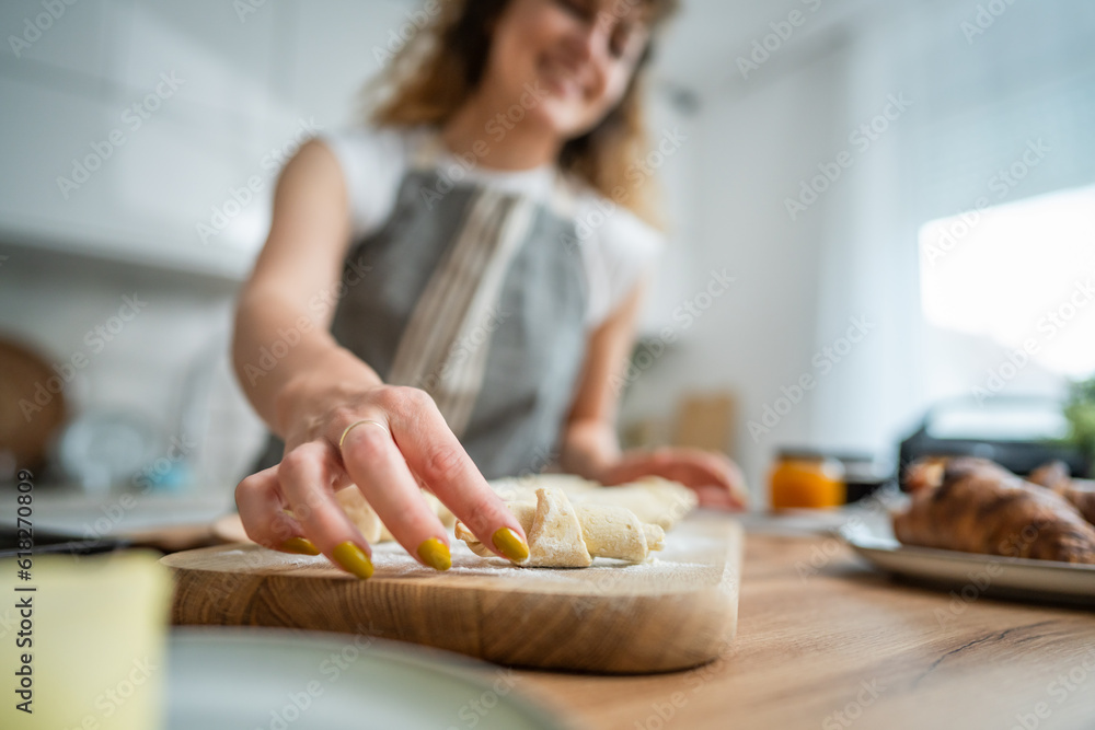 hands of unknown caucasian woman wear apron cook croissant in kitchen