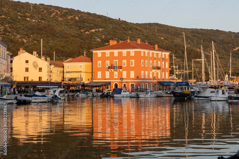 Kroatien- Stadt Cres: Abendstimmung im Hafen mit Spiegelung eines orangen Palastes