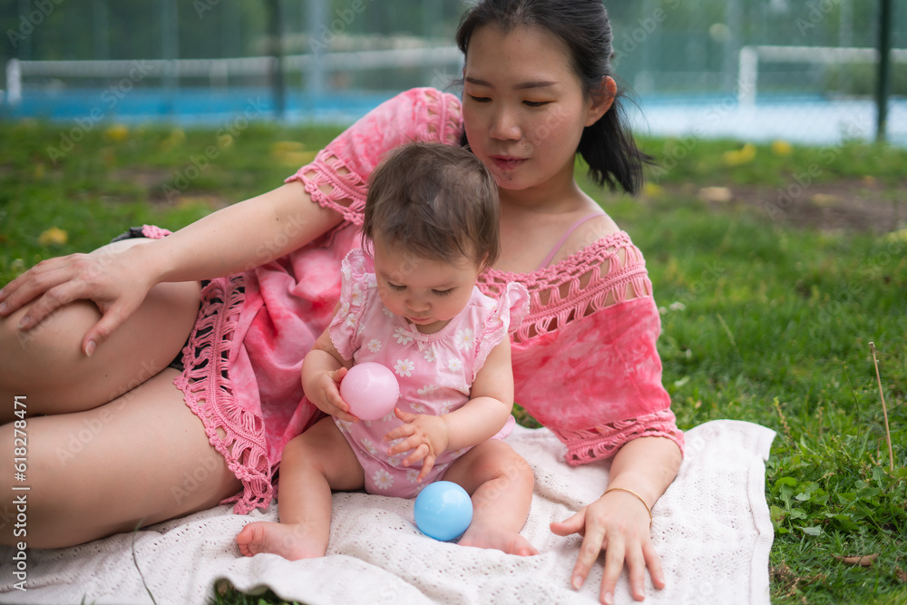 Asian mum and little child - young happy and beautiful Korean woman playing on city park with adorable and cheerful baby girl in mother and daughter love and bonding Asian mum and little child - young happy and beautiful Korean woman playing on city park with adorable and cheerful baby girl in mother and daughter love and bonding