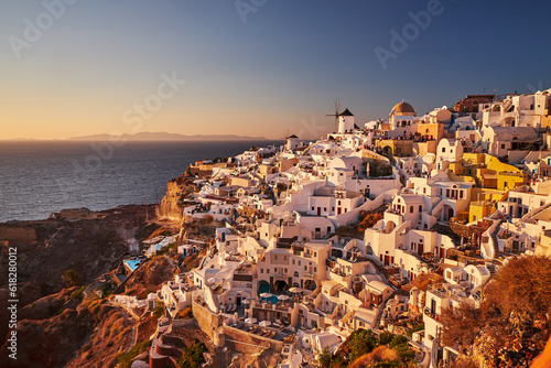 Beautiful view from the old castle of Oia village with traditional white houses and windmills in Santorini island in Aegean sea at sunset, Greece © Bruno