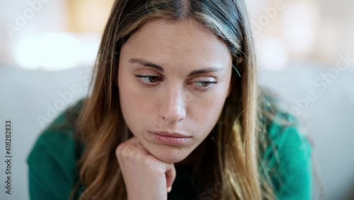 Video of beautiful young woman thinking and worried sitting on couch at home.