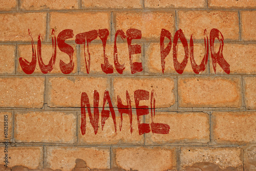 painting french text on brick wall meaning justice for child named nahel in Nanterre France photo