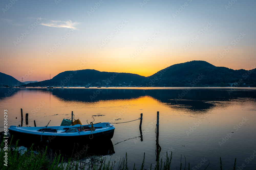 A long exposure of sunrise seascape with a small wooden boat in a bay.