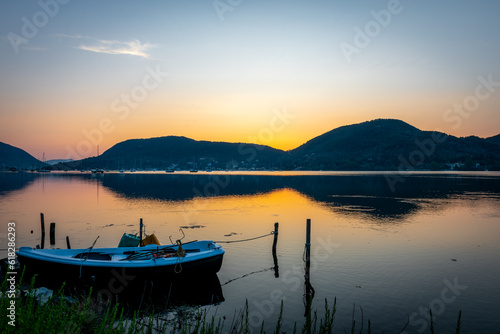 A long exposure of sunrise seascape with a small wooden boat in a bay. © Ming
