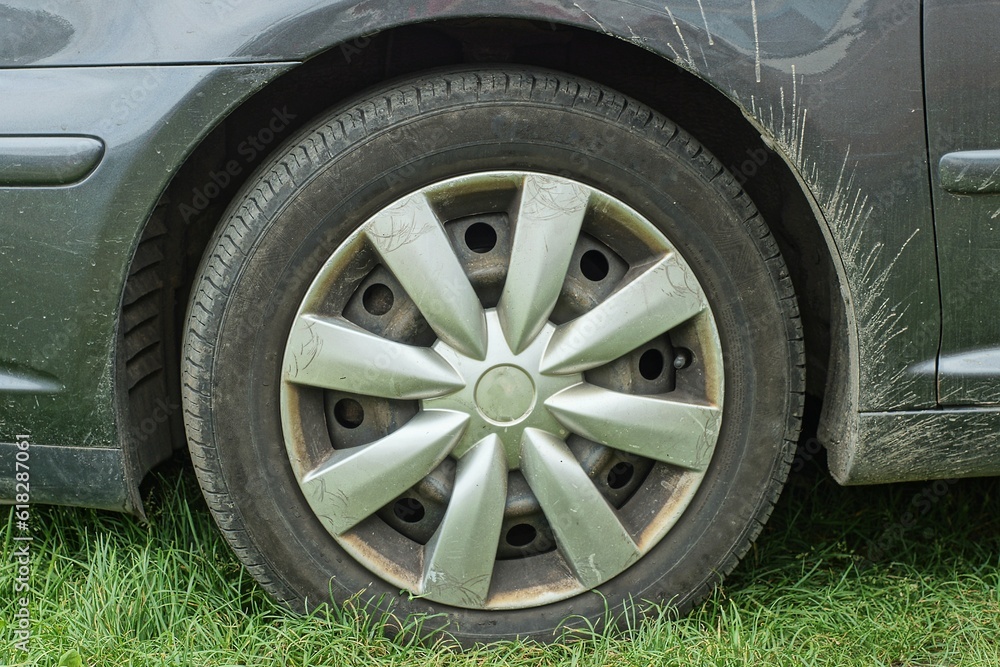 one modern car new with black rubber tyre, wheel and iron rim from gray toyota on green grass outdoors at daytime