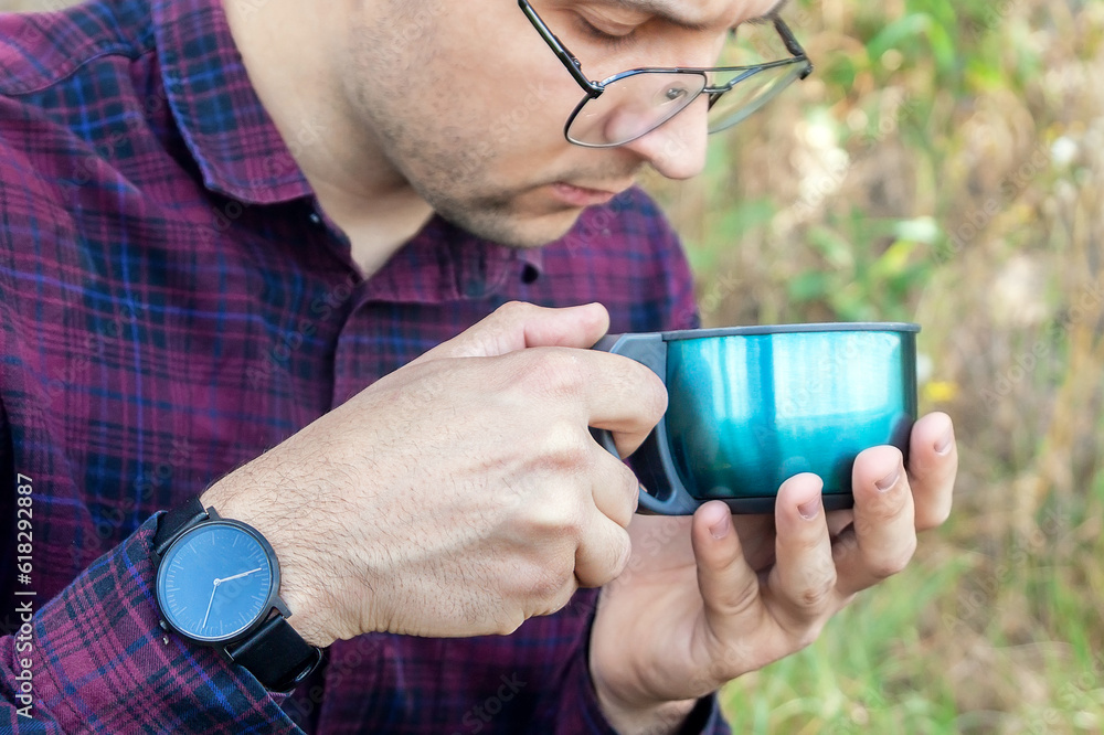 Rest with hot tea in hand. Man outdoors in the park. Recreation Rest with hot tea in hand. Man outdoors in the park. Recreation