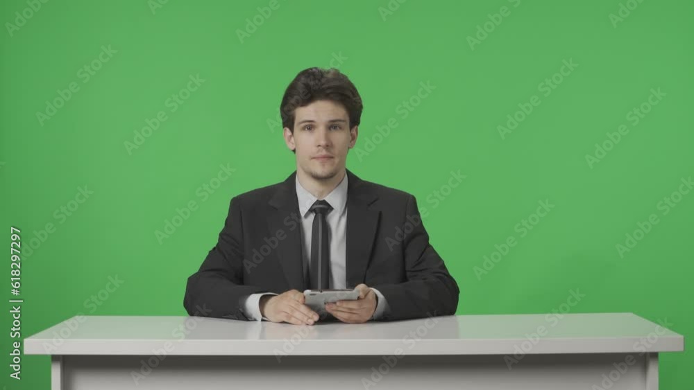 A presenter covering current events. A man browses, reads information from a tablet against the background of a green screen. Advertising area, workspace mock up. HDR BT2020 HLG Material. A presenter covering current events. A man browses, reads information from a tablet against the background of a green screen. Advertising area, workspace mock up. HDR BT2020 HLG Material.