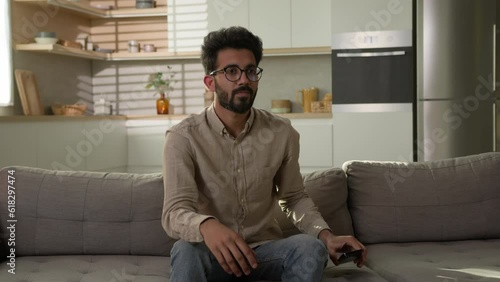 Arabian Indian man guy using mobile phone in kitchen put down smartphone stress free breathe and meditate on couch yoga exercise namaste relax healthy mindset zen calm meditation spiritual awareness