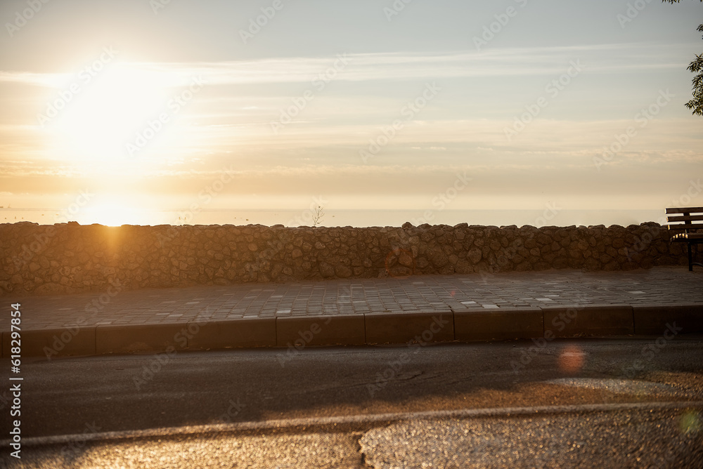 Sunny promenade by the sea at sunrise. The sidewalk is paved. Road by the sea for jogging, sports.