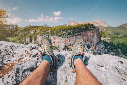 Hiker legs with trekking shoes on top of the canyon cliff. Outdoors activity and skyrunning concept photo