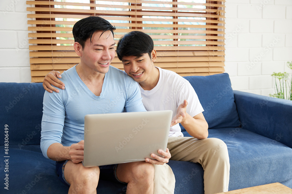 LGBT gay couple using laptop computer on sofa LGBT gay couple using laptop computer on sofa