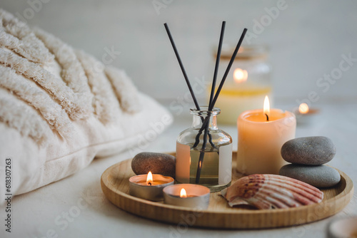 Burning candles on bamboo tray, cozy home atmosphere. Relaxation, detention zone in the living or bedroom. Stones, sea shells as decor. Apartment natural aroma diffusor with ocean breeze fragrance.