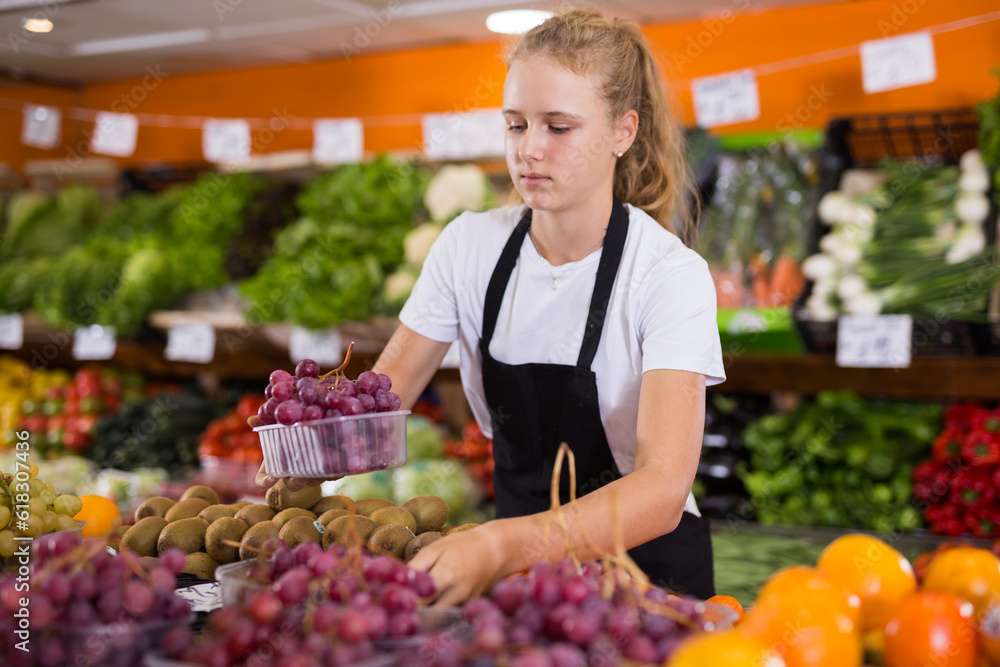 Portrait of teenage girl working in grocery shop as job experience, selling fresh grape