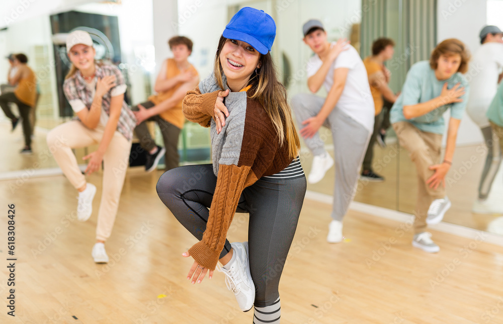 Fototapeta premium Emotional brunette teen b-girl dancing with group of friends in dance studio. Hip-hop generation.