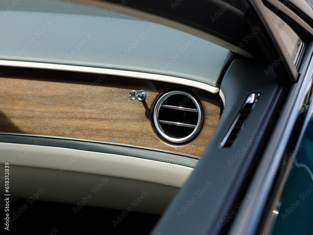 Detail of ventilation nozzle in the interior of a luxury car with wood and leather trim