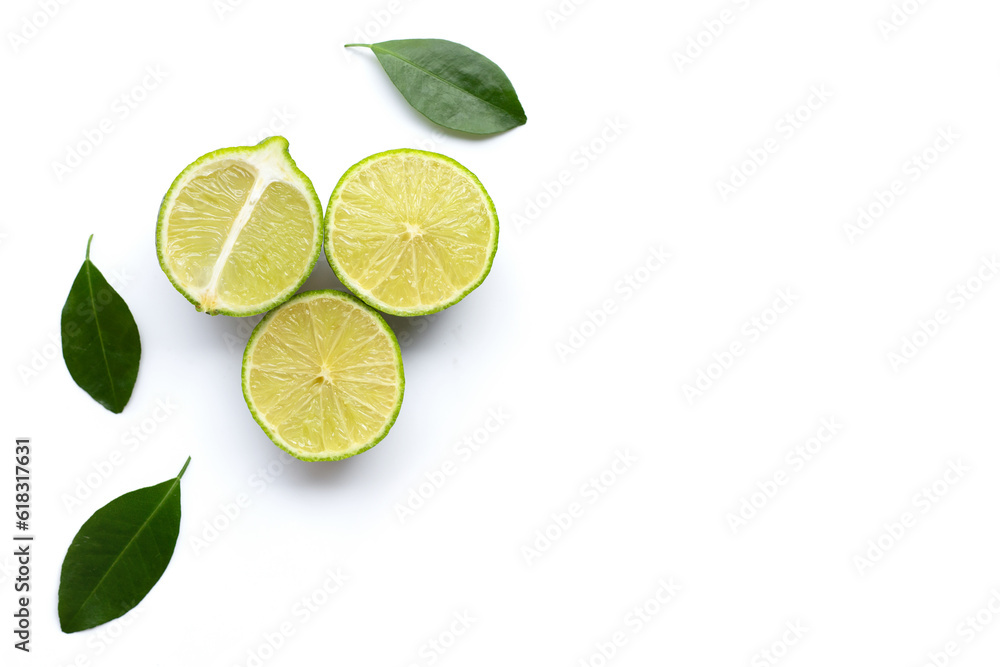 Ripe limes with green leaves on white.