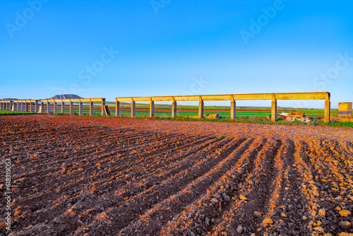 Paisaje de campos de cultivo para la agricultura con un canal de regadío bañado por los rayos dorados del sol al atardecer un buen día con cielo azul. photo