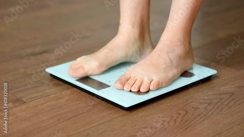 White floor scales and women's feet standing on them. A tailor's centimeter or measuring tape lying nearby to measure body changes. The concept of a healthy lifestyle and body weight tracking