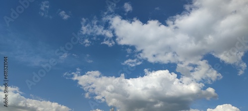 White fluffy clouds. Sunny spring day. White clouds of various shapes and sizes hang high in the sky. Above them is a light blue sky. The clouds are like airy soft cotton wool.