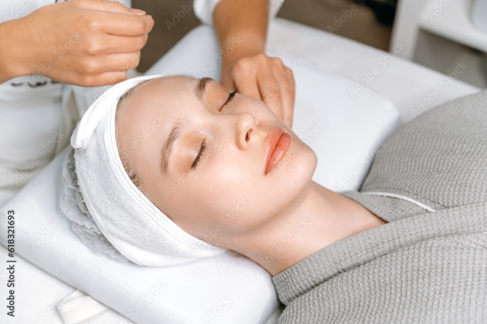 Close-up of a gorgeous caucasian young woman lying on a couch in a spa salon with her eyes closed, getting ready for facial treatments, massage, moisturizing mask. Spa beauty salon