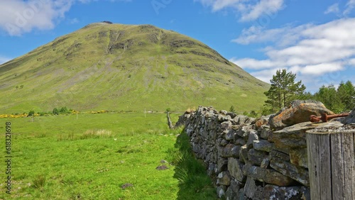 Ancient Stone fence leading towards Beinn Dorain mountain in the Scottish highlands with iconic grassy meadows and fields, Scotland photo