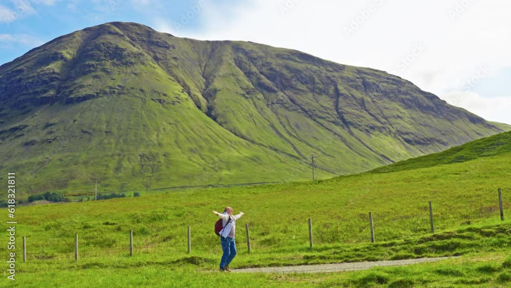 Happy hiker spinning around in excitement at the majestic view of the grassy Scottish Highlands on a sunny summer day, Scotland Happy hiker spinning around in excitement at the majestic view of the grassy Scottish Highlands on a sunny summer day, Scotland
