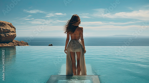Photographie a young pretty woman in a bikini standing by a pool and looking at the sea