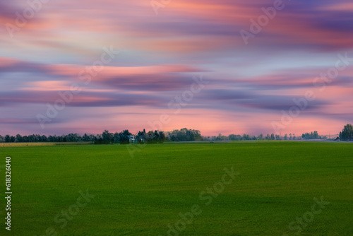 View from road trip landscape with field. Green fields and orange sky during the sunset,