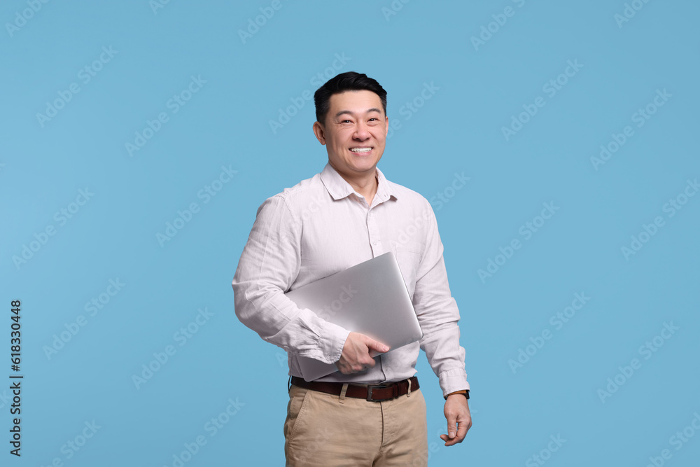 Happy man with laptop on light blue background