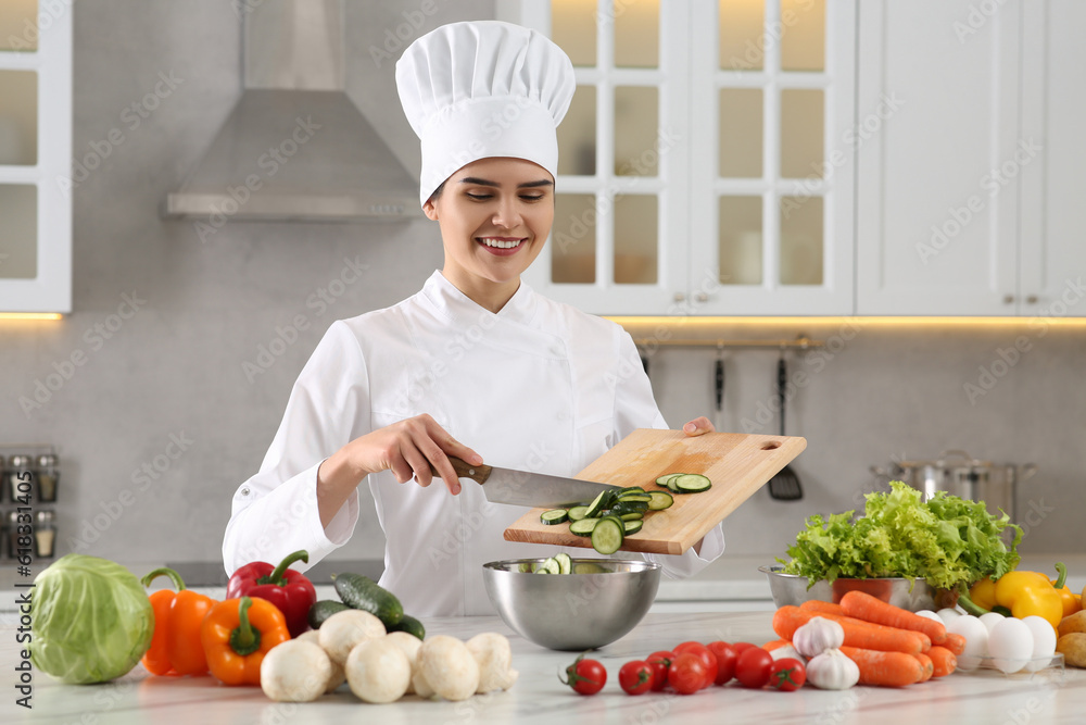 Professional chef putting cut cucumber into metal bowl at white marble table in kitchen Professional chef putting cut cucumber into metal bowl at white marble table in kitchen