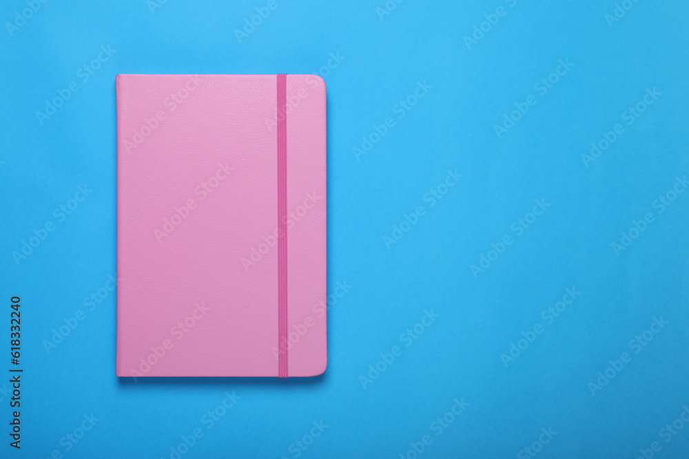Pink notebook on light blue background, top view. Space for text Pink notebook on light blue background, top view. Space for text