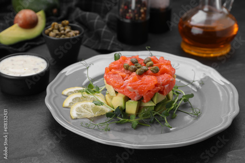 Delicious salmon tartare served with avocado and lemon on dark table