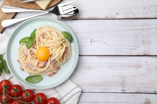 Delicious pasta Carbonara with egg yolk served on white wooden table  flat lay. Space for text