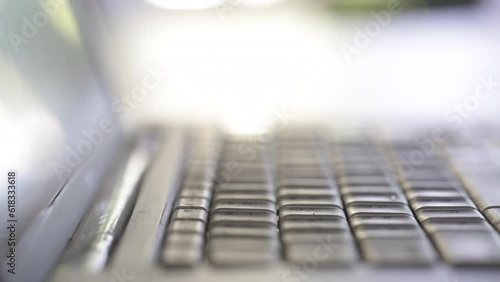 close up of fingers typing on silver laptop keyboard selective focus