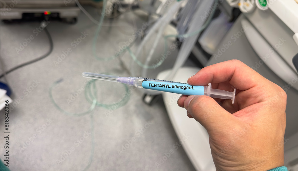 hand holds a syringe amidst IV drips and medications, symbolizing medical care, treatment, and the use of drugs in a hospital setting hand holds a syringe amidst IV drips and medications, symbolizing medical care, treatment, and the use of drugs in a hospital setting