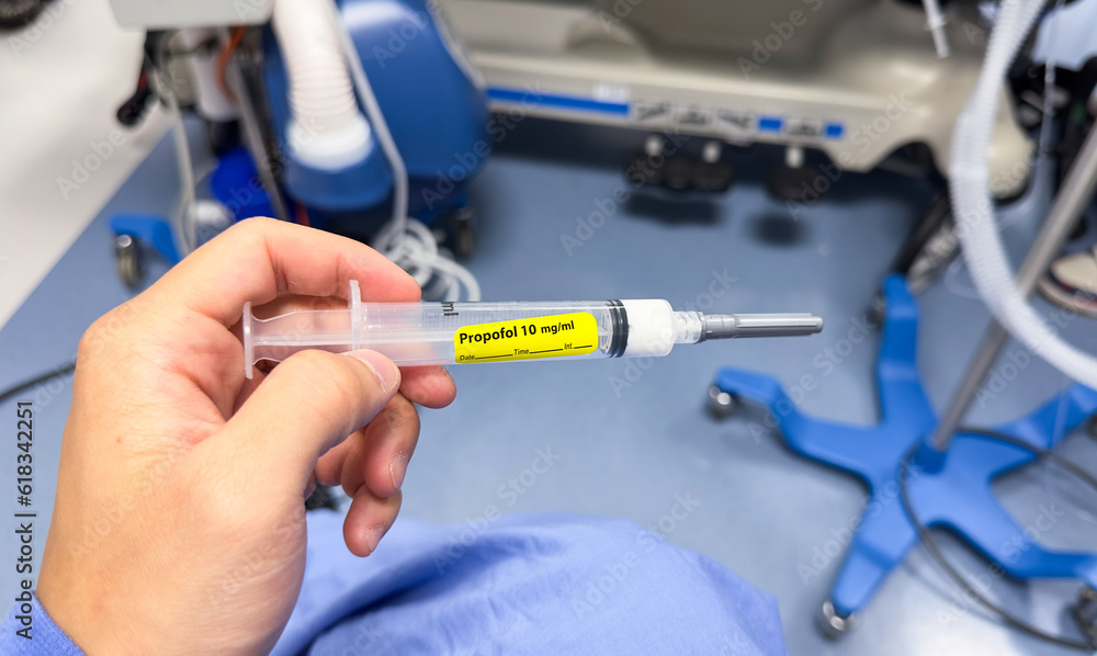 hand holds a syringe amidst IV drips and medications, symbolizing medical care, treatment, and the use of drugs in a hospital setting hand holds a syringe amidst IV drips and medications, symbolizing medical care, treatment, and the use of drugs in a hospital setting