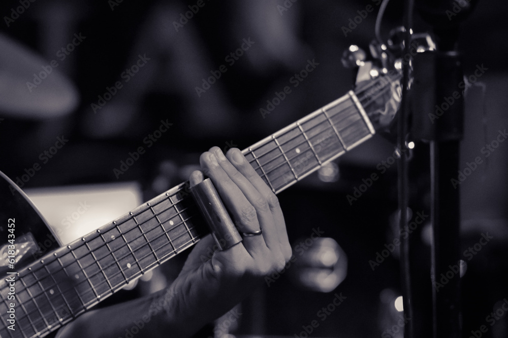 Details of an acoustic guitar, with emphasis on the hand of the blues