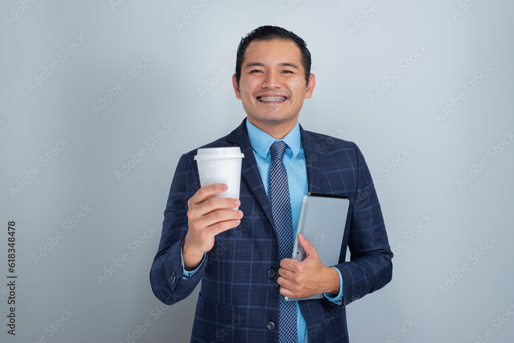 dark skinned mexican young man smiles while holding a cup of coffee and tablet ready for marketing business work dark skinned mexican young man smiles while holding a cup of coffee and tablet ready for marketing business work