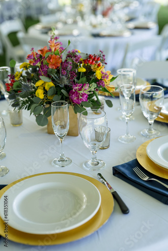 Table setting for wedding event with glass, chargers and colorful flowers