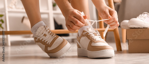 Bild auf Leinwand Woman in stylish sneakers tying shoe laces in shop