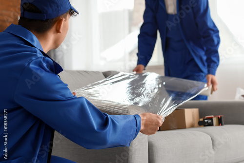 Male movers wrapping sofa w...