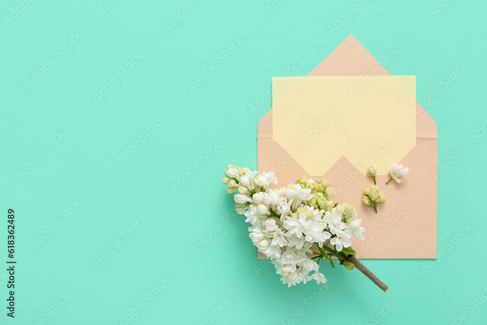 Envelope with blank card and lilac flowers on turquoise background Envelope with blank card and lilac flowers on turquoise background